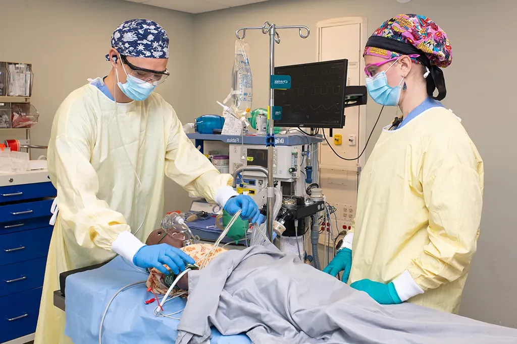 Two U N E D N P students practice on a patient simulator